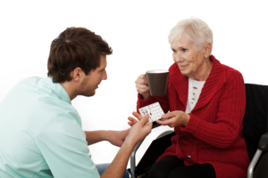 caregiver giving medicine to an elderly woman